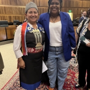 À esquerda, Elisa Loncón, mulher indígena que veste roupas tradicionais do Chile. À direita, a secretária adjunta, Caroline Moreira, mulher negra com cabelo preto trançado, que veste camisa branca e blazer azul.

Autoria da descrição da foto: Wagner Meirelles Ascom SJCDH