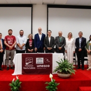 Doze autoridades em pé atrás de uma mesa com os logos  do Geoparque Quarta Colônia e Unesco